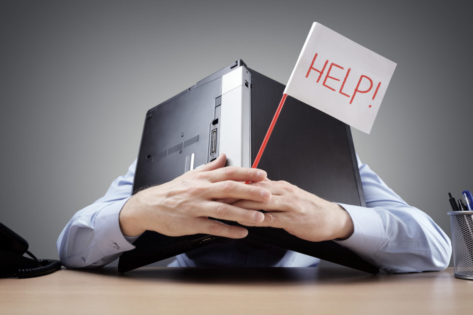 Businessman burying his head uner a laptop asking for help